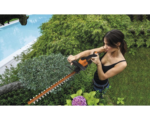 Kvinna klipper häck med en häcksax i trädgården