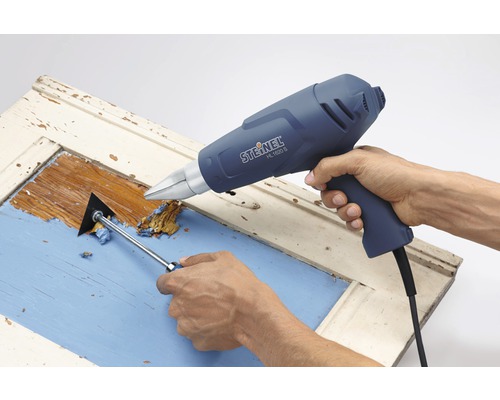 Ta bort färg från en dörr med en varmluftspistol och en spackel