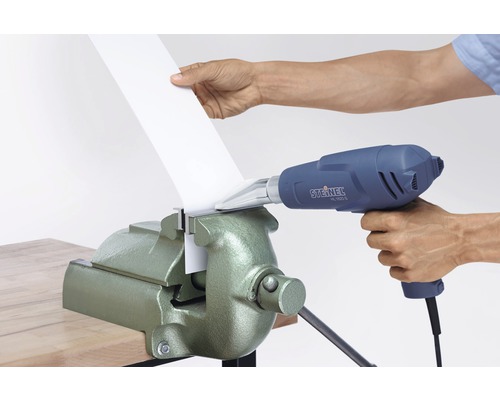 En person böjer plast med en varmluftspistol och ett skruvstäd.