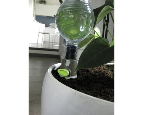 Automatisk växtvattnare med vattenflaska i vit blomkruka