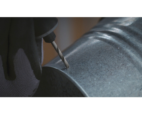 En person borrar ett hål i ett galvaniserat rör.