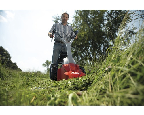 Man använder en AL-KO slåtterbalk i ett fält med högt gräs.