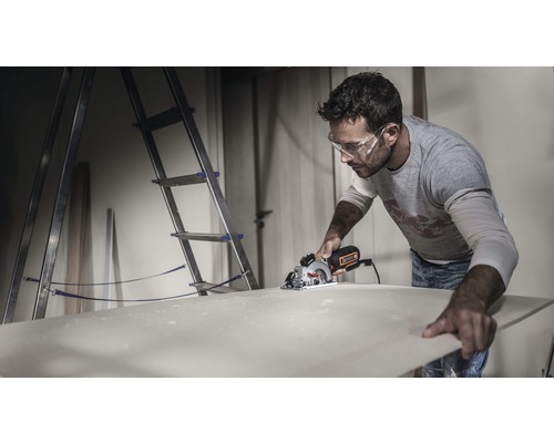 Man sågar träskiva med handhållen cirkelsåg i verkstad