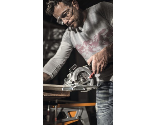 Man sågar träplanka med cirkelsåg på en arbetsbänk