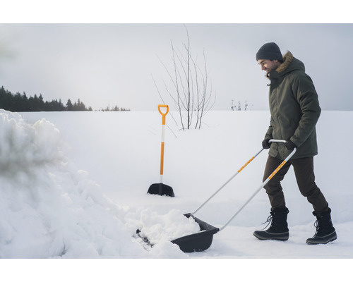 Man skottar snö med en snöskyffel på vintern