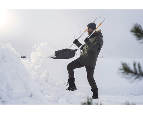 En person skottar snö med en snöskyffel.