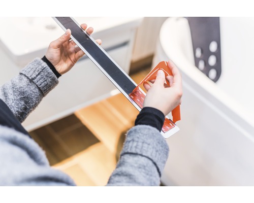 Person tar bort skyddsfolie från halkskyddsremsa