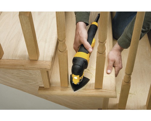 En person använder ett multifunktionsverktyg för att slipa en trätrappa.