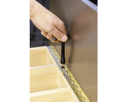 Hand skruvar fast gångjärn på trästruktur med skruvmejsel