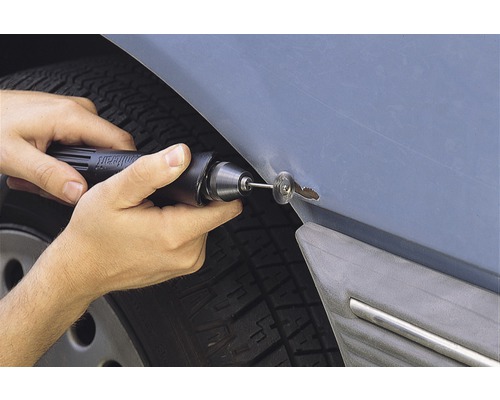 Person som reparerar rostfläck på bil med roterande verktyg