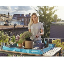Kvinna planterar blommor på balkongen med en planteringsmatta från Gardena