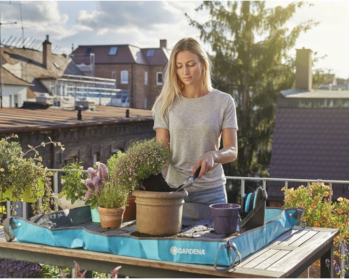 Kvinna planterar blommor på balkongen med en planteringsmatta från Gardena