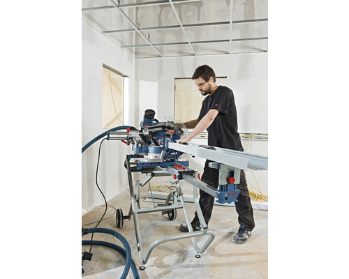 En man arbetar med en kapsåg på en byggarbetsplats för att såga ett arbetsstycke.