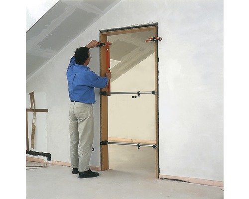 Man installerar en dörr med en dörrspridare i en råbyggnad