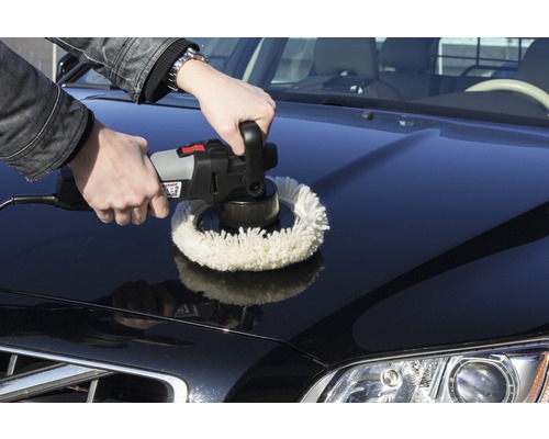 En man polerar motorhuven på en bil med en polermaskin.