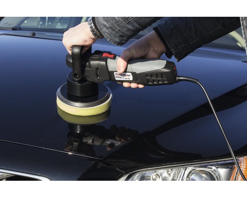 En person polerar en bil med en polermaskin.