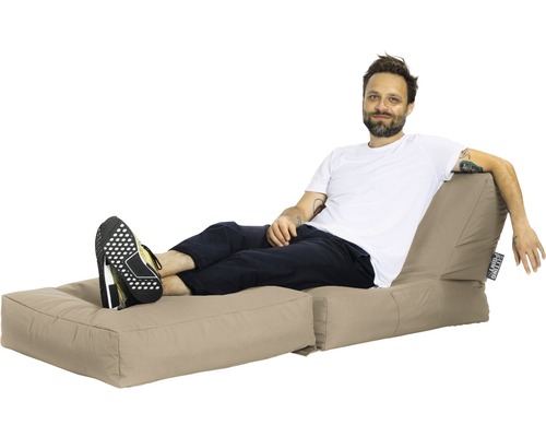 Man slappnar av på en beige sittsäck med fotstöd