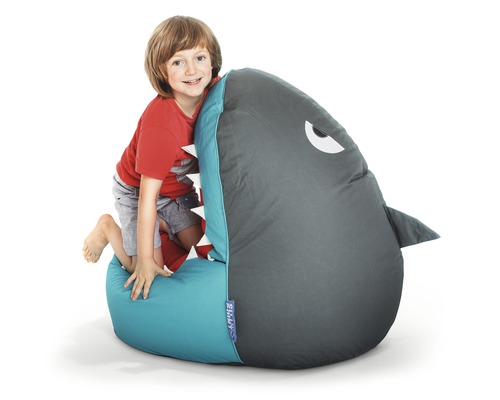 Pojke klättrar på en sittsäck i form av en haj.