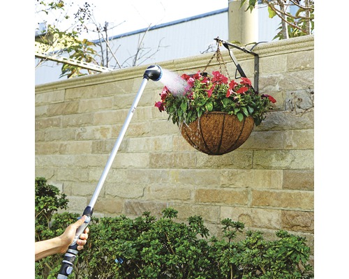 Trädgårdsbevattning med en sprutmunstycke på en bom för att vattna en hängande växt