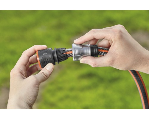 Två händer ansluter en slangkoppling till en trädgårdsslang.