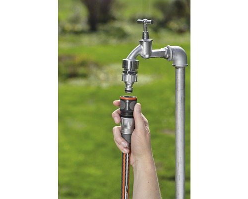 En person ansluter en trädgårdsslang till en vattenkran med hjälp av en slangkoppling.