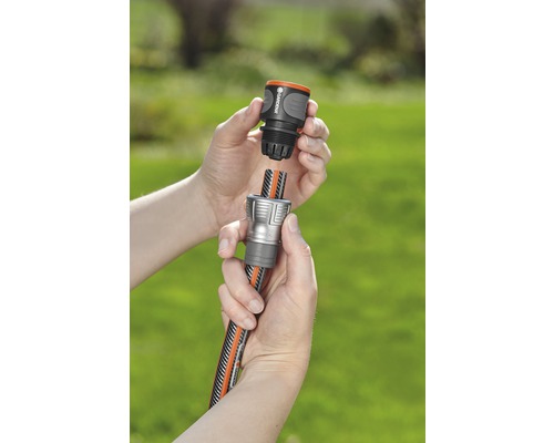 Två händer kopplar ihop en trädgårdsslang med en slangkoppling.