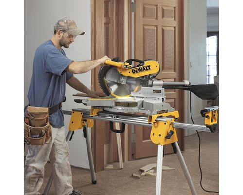 En man använder en DeWalt kap- och gersåg på ett underrede i ett rum.