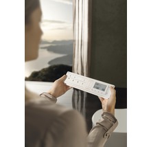 Kvinna håller ett hemautomationssystem i ett badrum.