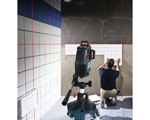 Scenen visar en plattsättare som arbetar med en linjelaser för att rikta in plattor.