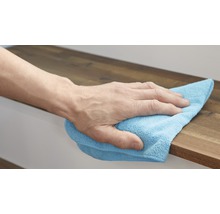 En hand torkar av en träyta med en rengöringsduk.