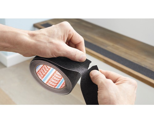 Person rullar ut Tesa halkskyddstejp för att applicera den på ett trappsteg