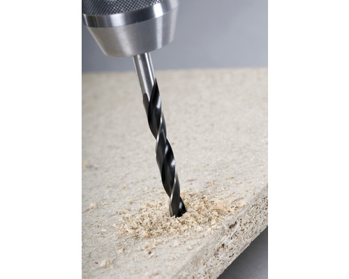 En borrmaskin borrar ett hål i en träskiva.