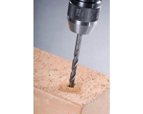 Närbild av en borr som borrar ett hål i en tegelsten.