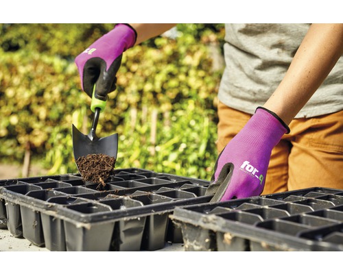 Person fyller såtråg med jord och trädgårdsspade, skyddad av trädgårdshandskar