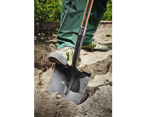 En person använder en spade för att gräva i trädgården.