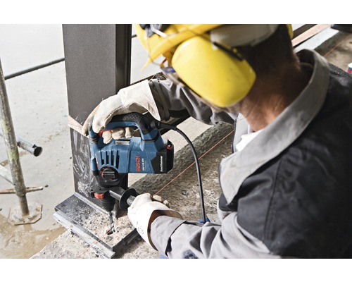 En arbetare borrar ett hål i en metallbalk med en Bosch GBH 3-28 F Professional borrhammare.