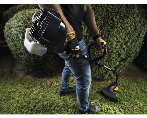 Man som klipper gräs i trädgården med en trimmer