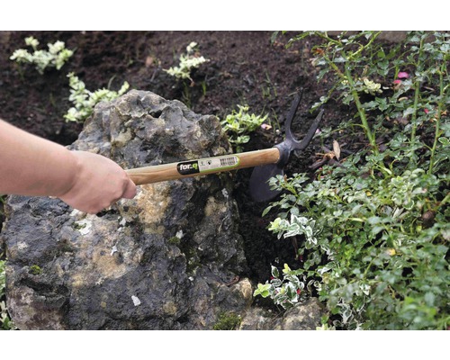 Trädgårdshacka med trähandtag som används i en trädgårdsbädd.