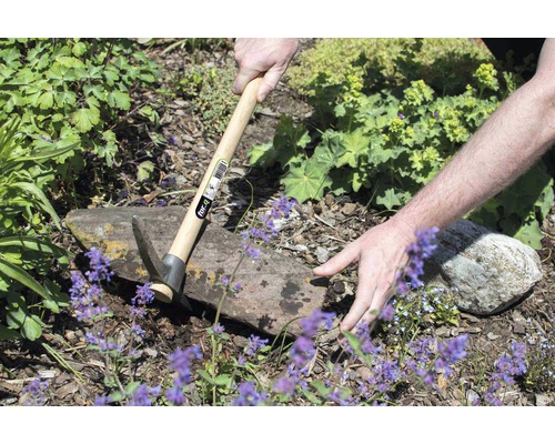 Person arbetar i trädgården med en hacka med trähandtag.