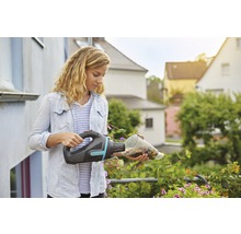 Kvinna tömmer en Gardena batteridriven handdammsugare ovanför blommor