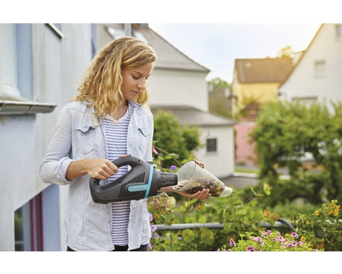 Kvinna tömmer en Gardena batteridriven handdammsugare ovanför blommor