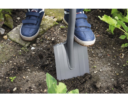 Person som trampar ner en spade i trädgårdsjorden