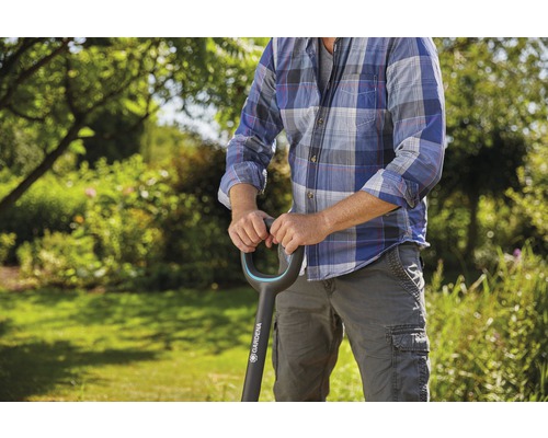 En person håller en Gardena-spade i trädgården.