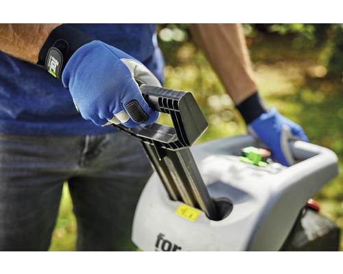 En person använder en trädgårdshack med arbetshandskar.