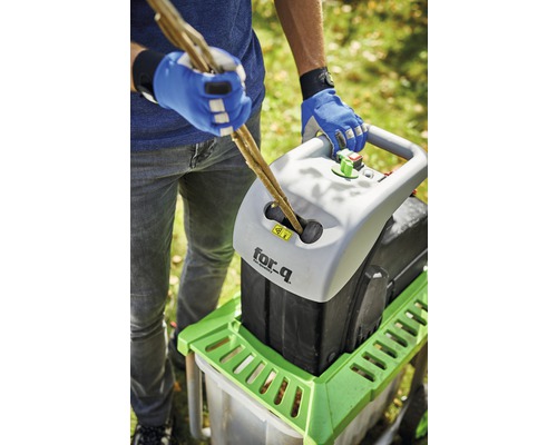 En person matar in grenar i en kompostkvarn av märket for_q.