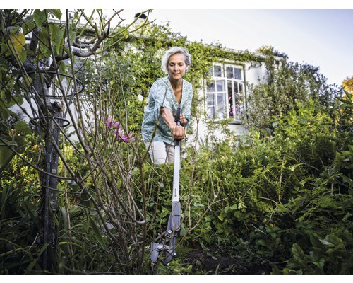 Kvinna använder en rotborttagare i trädgården för att ta bort ogräs