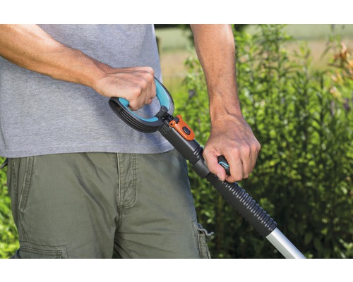 Närbild på en person som använder en gräsmattluftare eller vertikalskärare med handtag, för trädgårdsskötsel