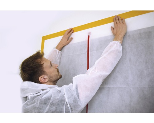 Hantverkare fäster dammskydd med tejp på väggen