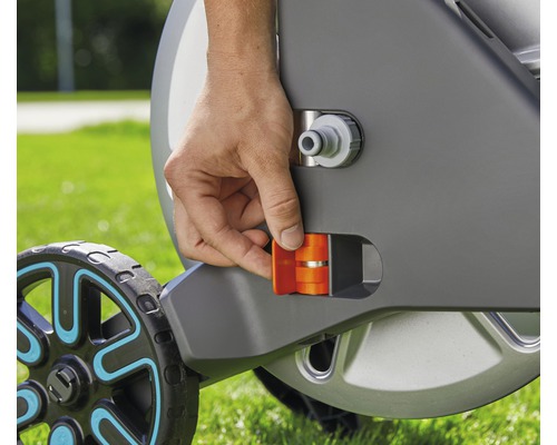 Närbild av en hand som manövrerar ett orange spärrlås på en trädgårdsslangvagn.