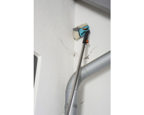 Fasadborste med teleskopskaft i bruk på en husvägg
